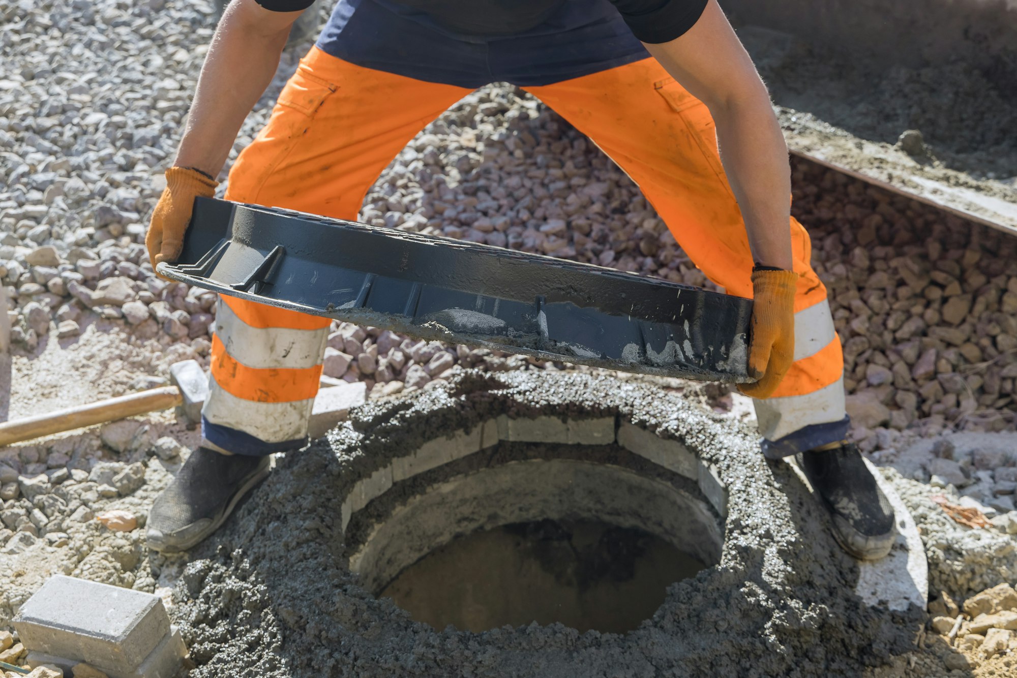 Sewerage construction with utility worker installing underground well manhole sewage